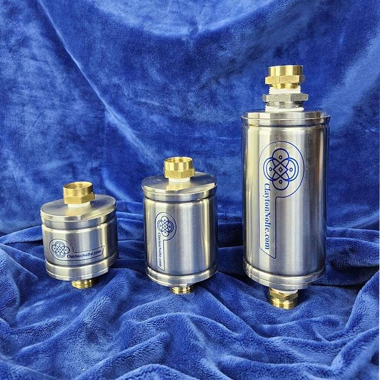 Three stainless steel Nature Harmony water structuring units on a blue cloth
